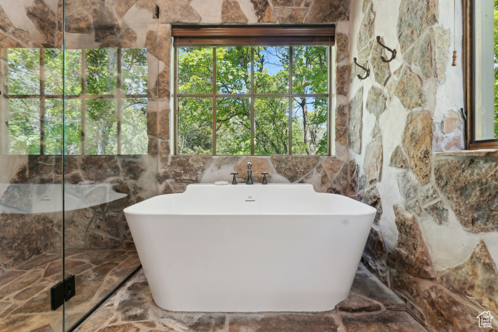 Full bath featuring a soaking tub and a marble finish shower