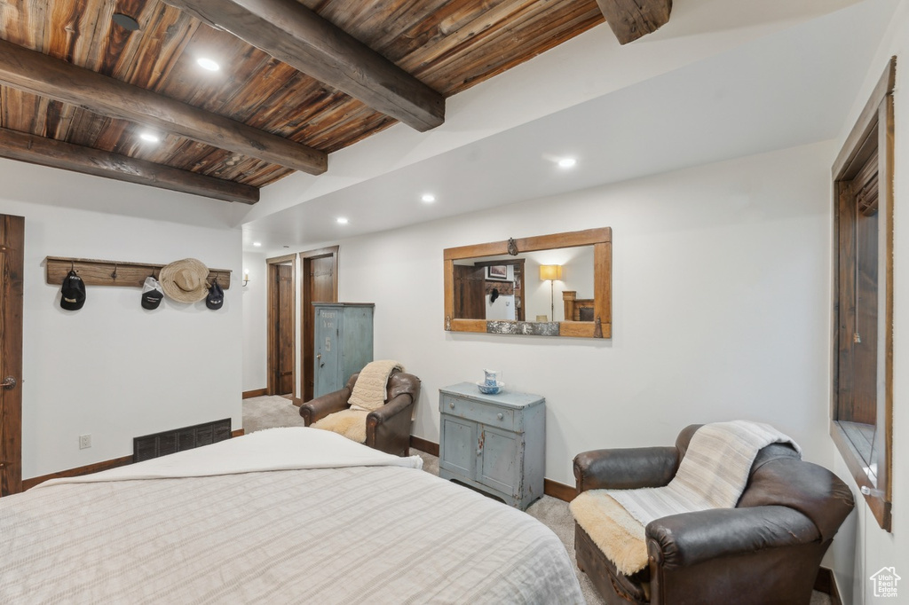 Carpeted bedroom with a wooden ceiling with exposed beams and recessed lighting