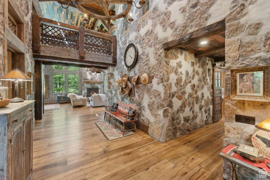 Living area with wood-type flooring, beamed ceiling, a lit fireplace, and a chandelier