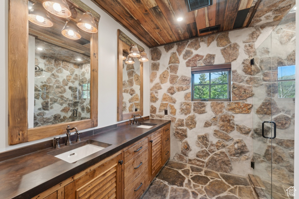 Full bathroom featuring wood ceiling, double vanity, and a shower stall