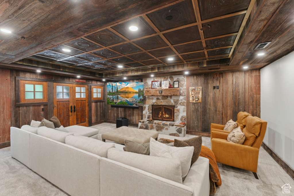 Carpeted living area with wooden walls, french doors, and a stone fireplace