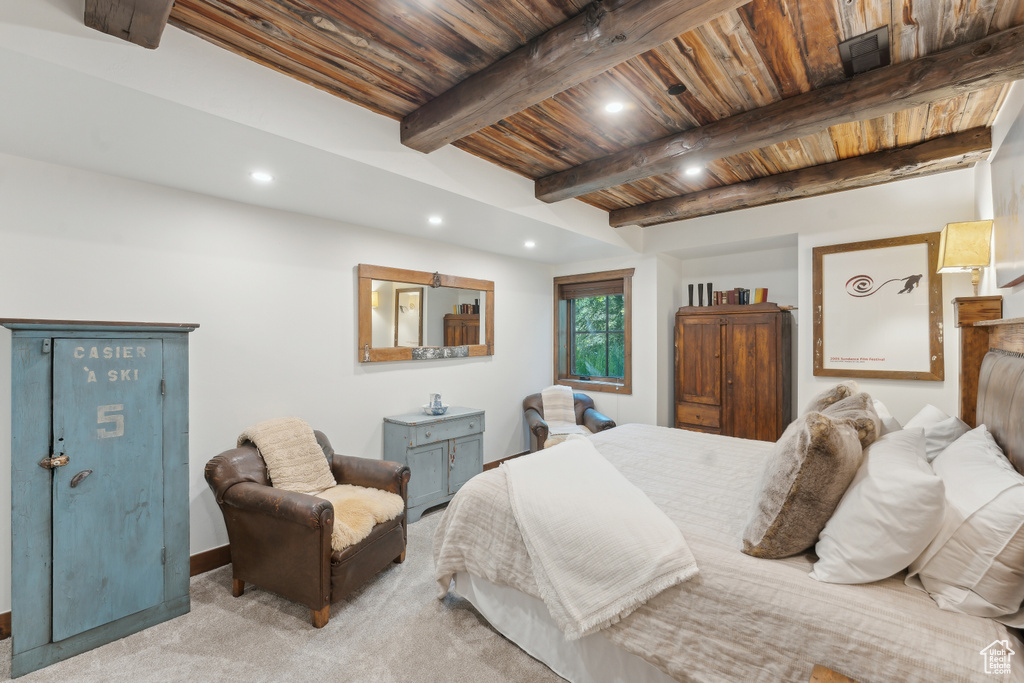 Carpeted bedroom with a wood ceiling with exposed beams and recessed lighting
