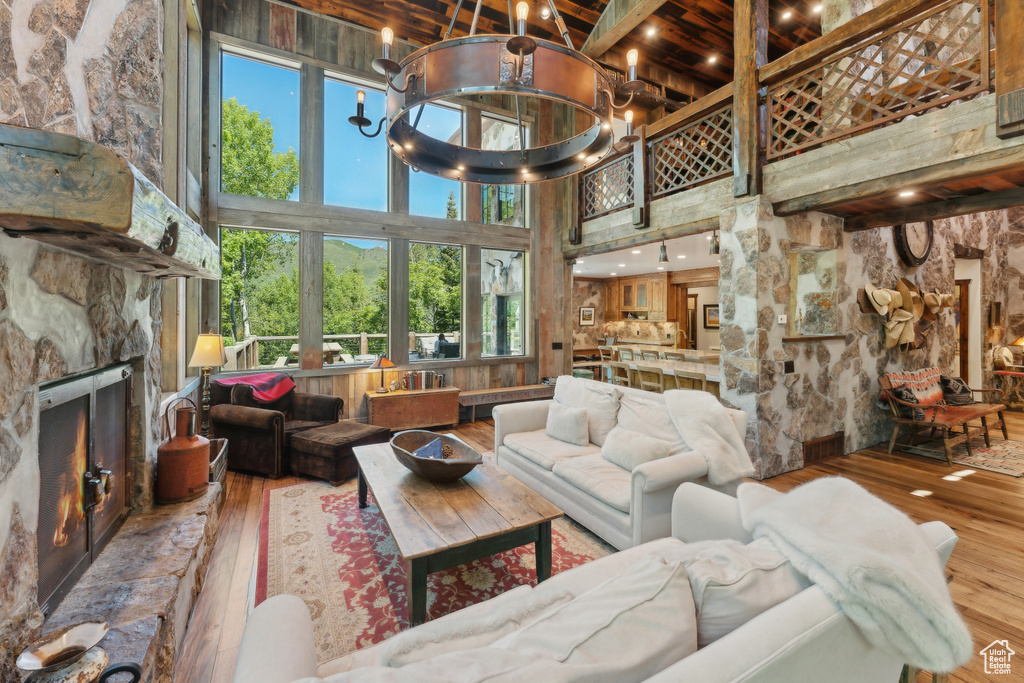 Living room featuring hardwood / wood-style flooring, a towering ceiling, a fireplace, beamed ceiling, and a chandelier