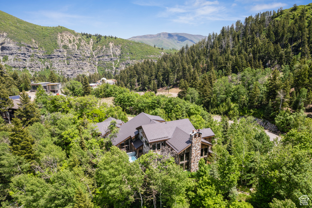 View of subject property featuring a mountain backdrop and a forest