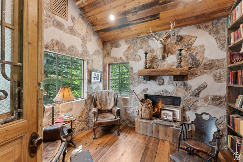 Living room with hardwood / wood-style floors, wood ceiling, high vaulted ceiling, and a stone fireplace