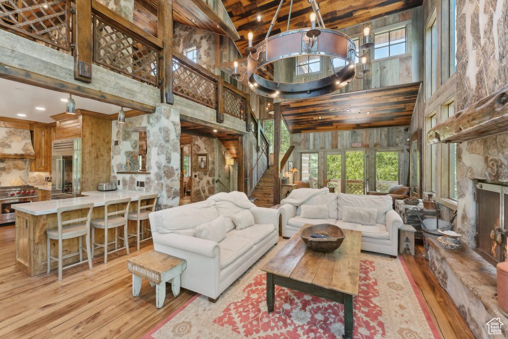 Living area with a towering ceiling, hardwood / wood-style floors, stairway, a chandelier, and wood walls