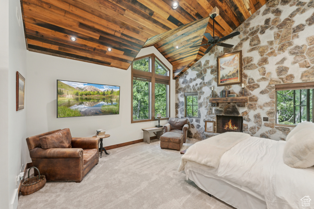 Carpeted bedroom with wood ceiling, high vaulted ceiling, and a stone fireplace
