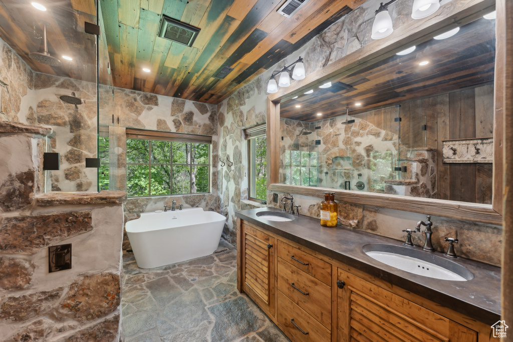 Bathroom featuring walk in shower, a soaking tub, double vanity, stone floors, and wooden ceiling