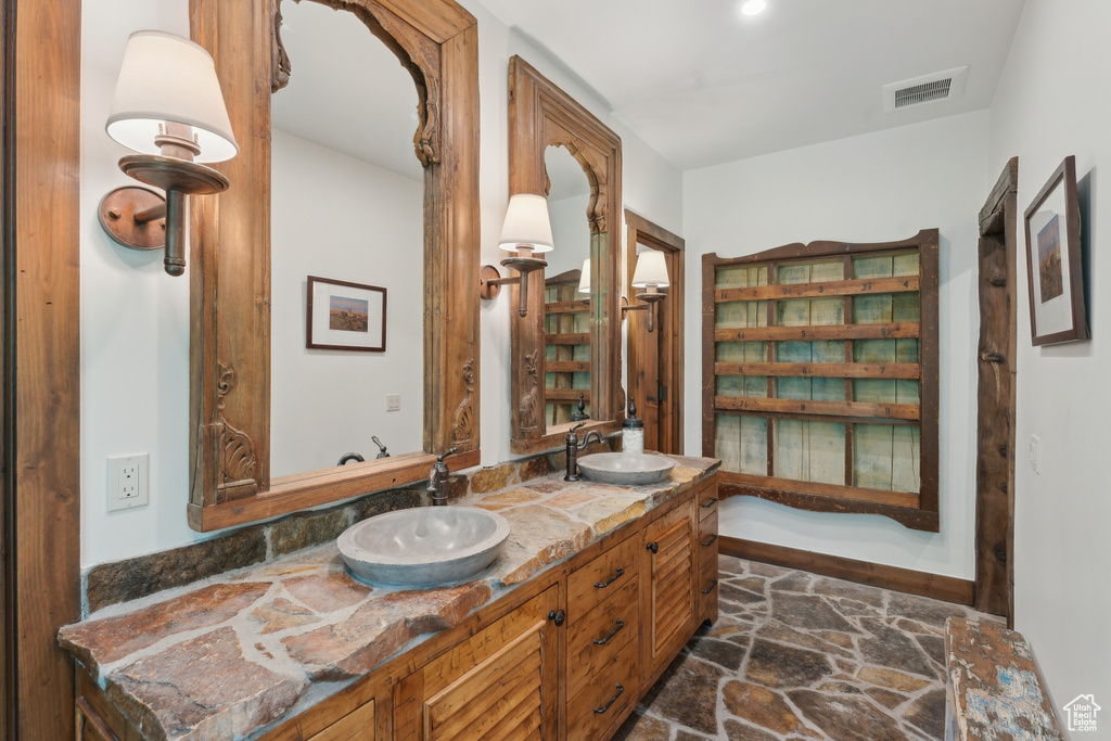 Full bath with double vanity and stone finish flooring