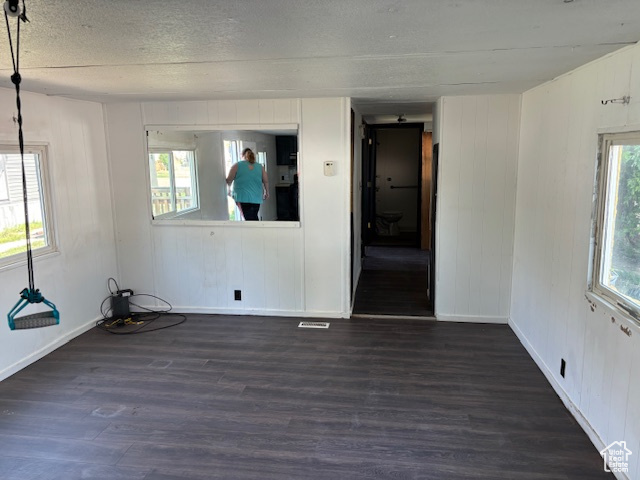 Unfurnished room featuring dark wood-type flooring and a textured ceiling