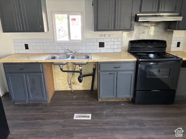 Kitchen with black range with electric cooktop, under cabinet range hood, gray cabinetry, dark wood-style flooring, and decorative backsplash