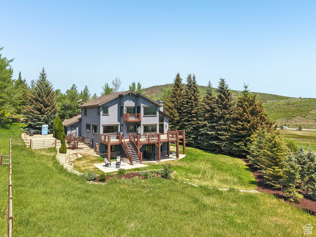 Back of property with a patio, a wooden deck, a yard, stairway, and stucco siding