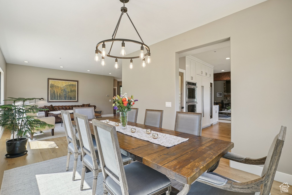 Dining area with light wood-style flooring, recessed lighting, and a chandelier