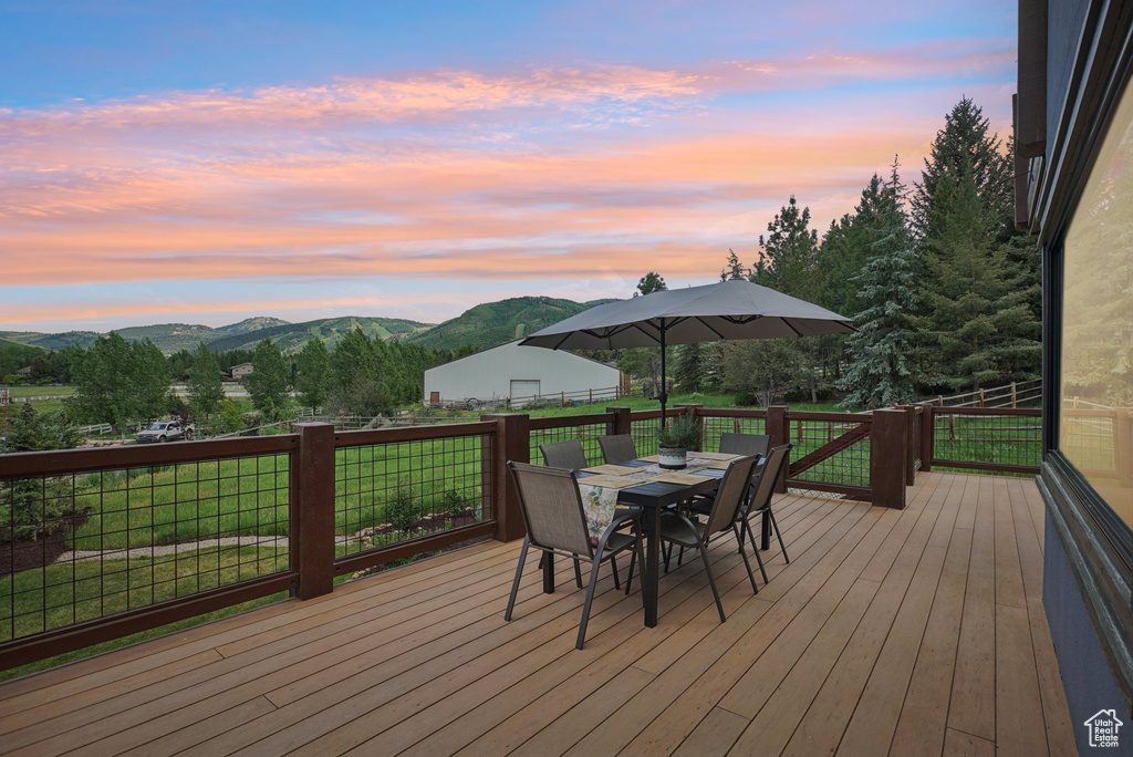 Deck at dusk featuring outdoor dining area and a mountain view