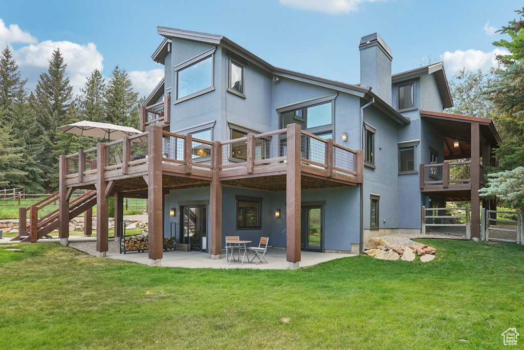 Rear view of property featuring a chimney, stucco siding, and a patio area