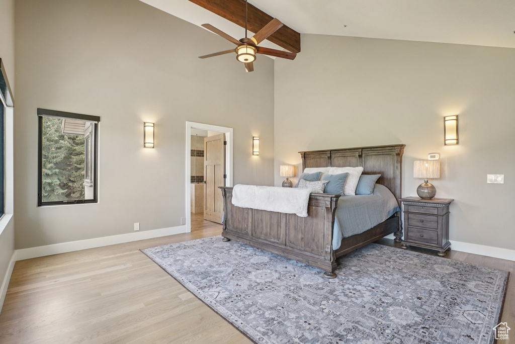 Bedroom featuring high vaulted ceiling, light wood-type flooring, beam ceiling, and ensuite bath