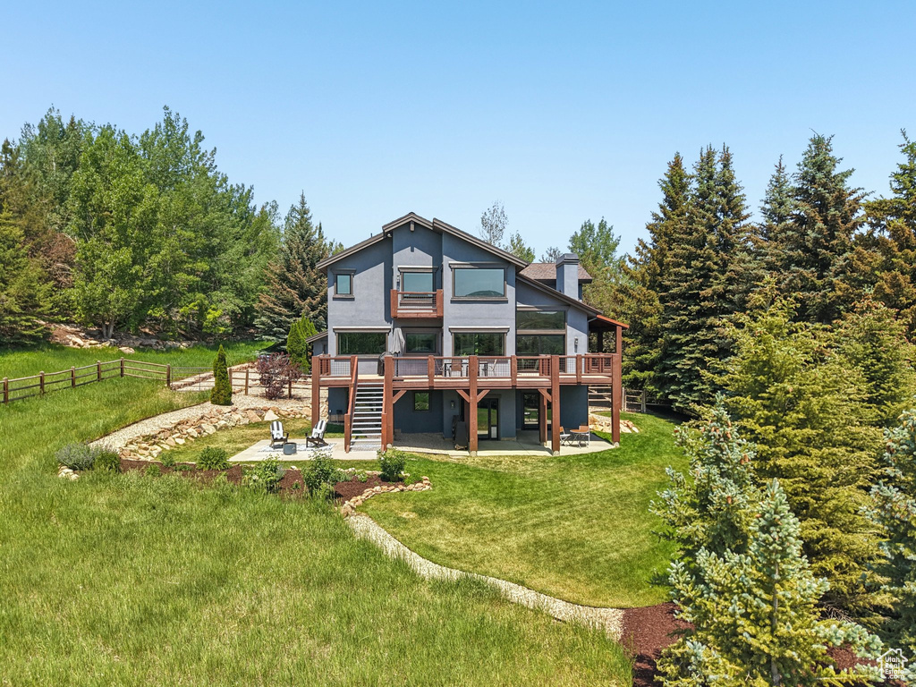 Back of house featuring a patio area, a wooden deck, stairs, and a chimney