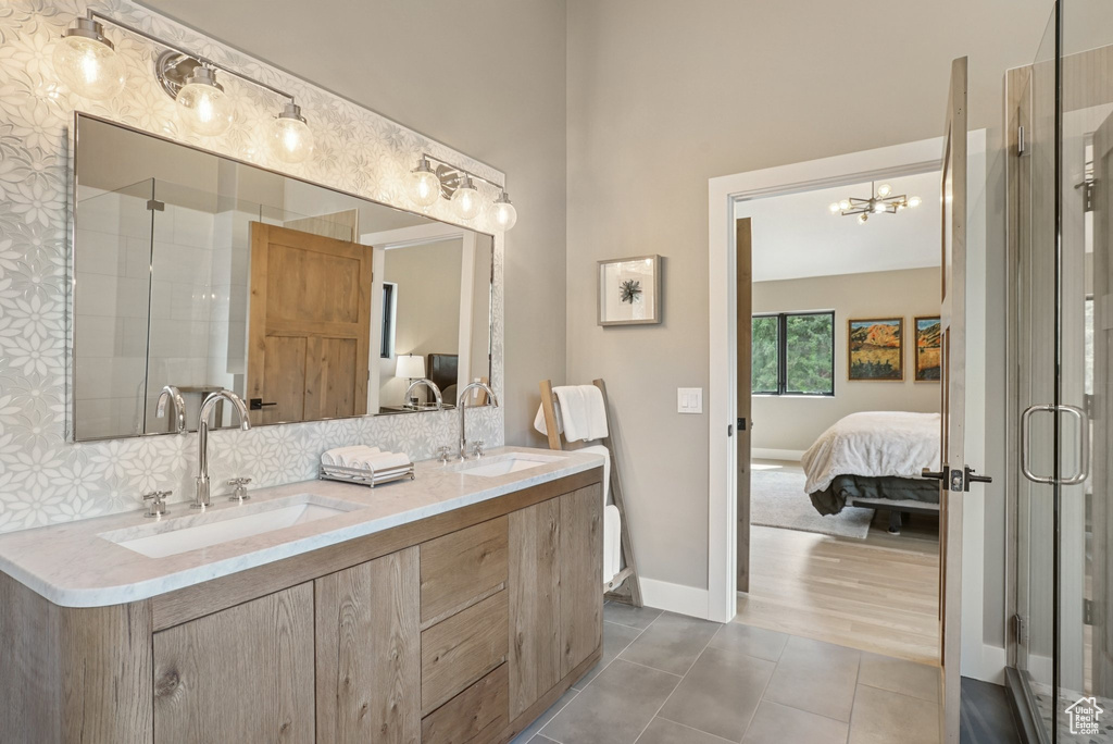 Bathroom featuring ensuite bathroom, double vanity, a stall shower, tile patterned flooring, and a chandelier