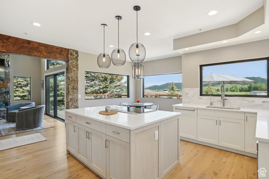 Kitchen with decorative backsplash, recessed lighting, black electric stovetop, light wood finished floors, and healthy amount of natural light