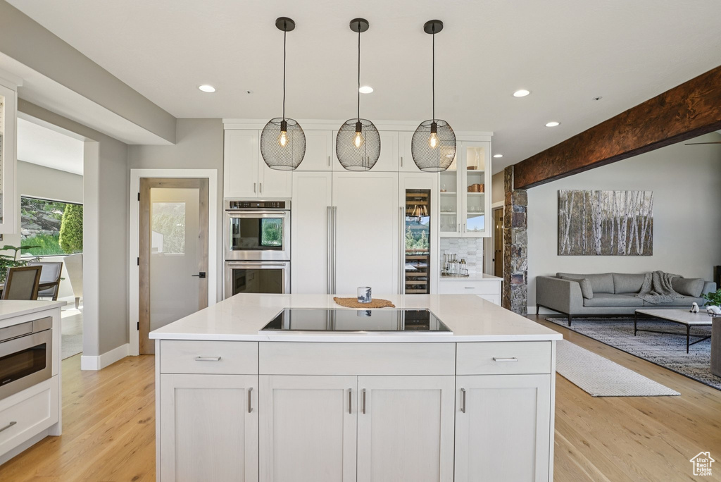 Kitchen with stainless steel appliances, white cabinets, light wood-type flooring, recessed lighting, and light countertops
