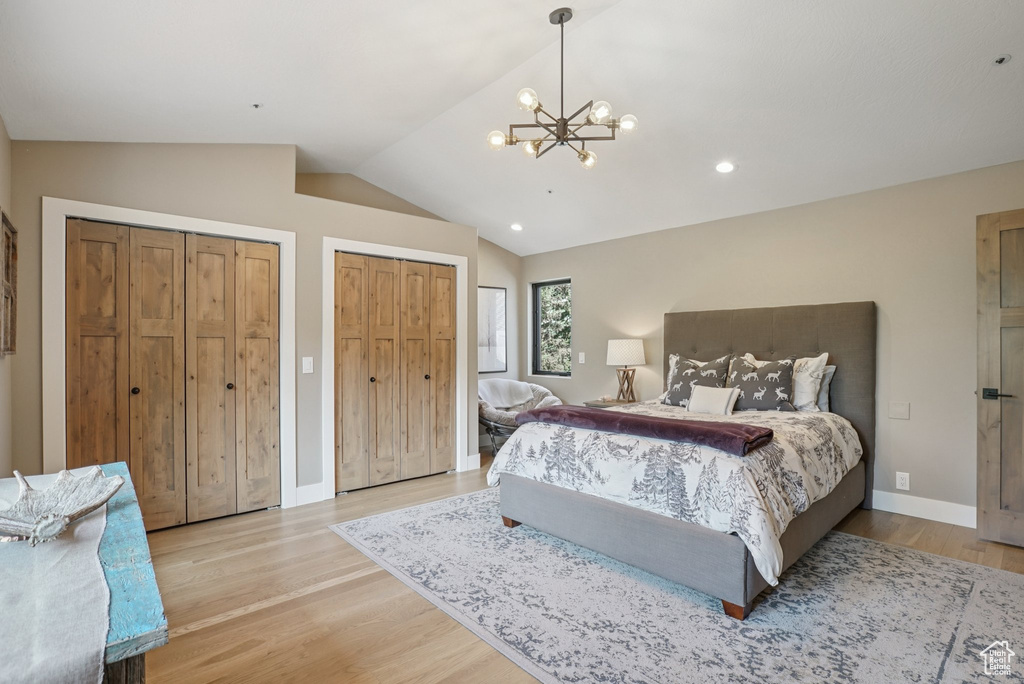 Bedroom featuring vaulted ceiling, multiple closets, light wood finished floors, a chandelier, and recessed lighting