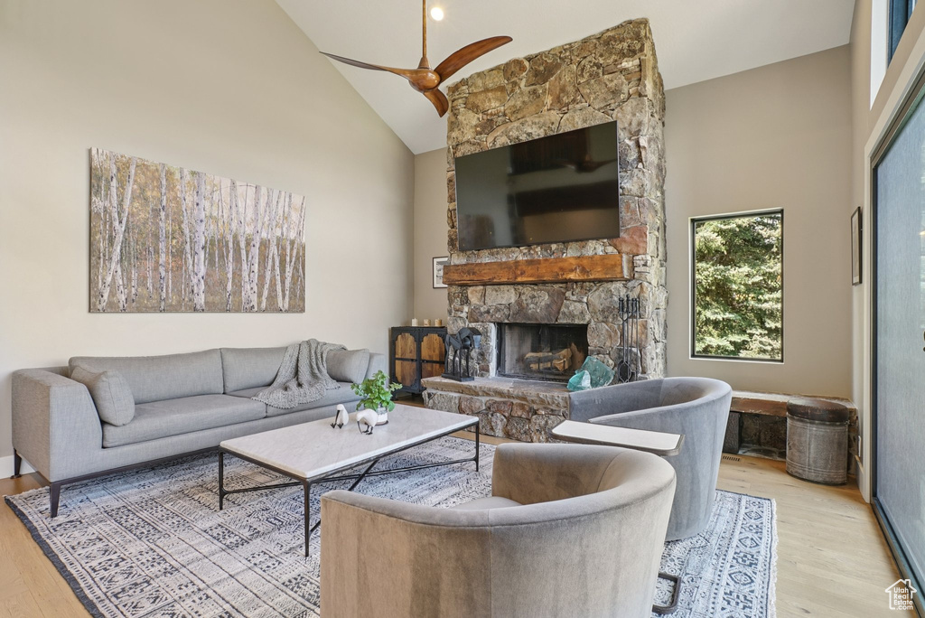 Living area featuring high vaulted ceiling, wood finished floors, a fireplace, and a ceiling fan