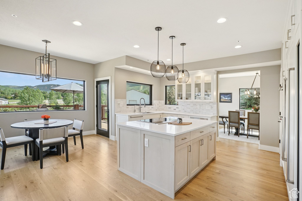 Kitchen featuring a chandelier, light countertops, backsplash, glass insert cabinets, and white cabinetry