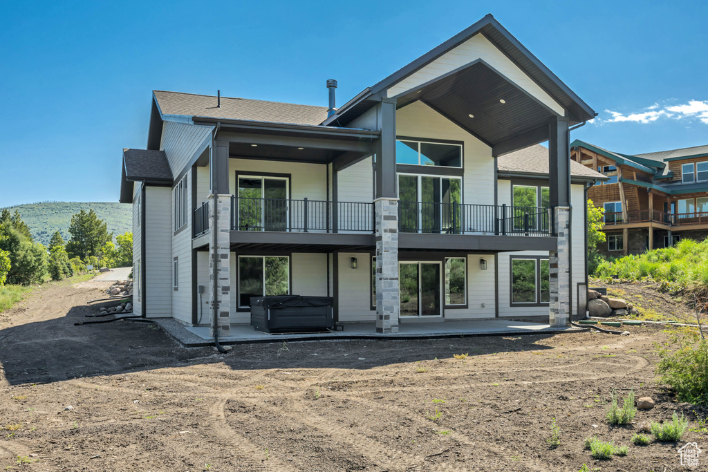 Rear view of property with a balcony, a hot tub, and a patio area