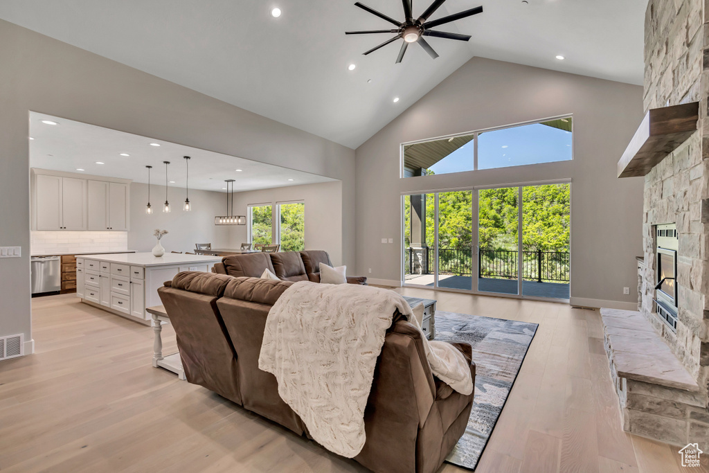 Living area with recessed lighting, a fireplace, a ceiling fan, high vaulted ceiling, and light wood-style flooring