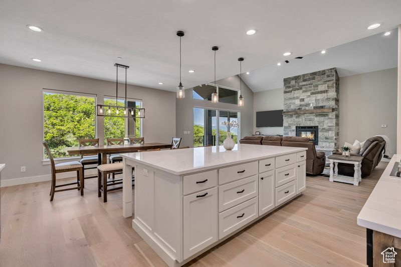 Kitchen featuring healthy amount of natural light, light wood-type flooring, white cabinets, recessed lighting, and vaulted ceiling