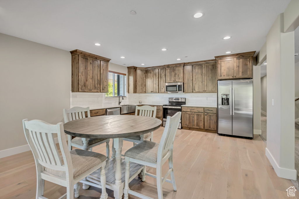 Kitchen featuring appliances with stainless steel finishes, tasteful backsplash, light wood finished floors, recessed lighting, and light countertops