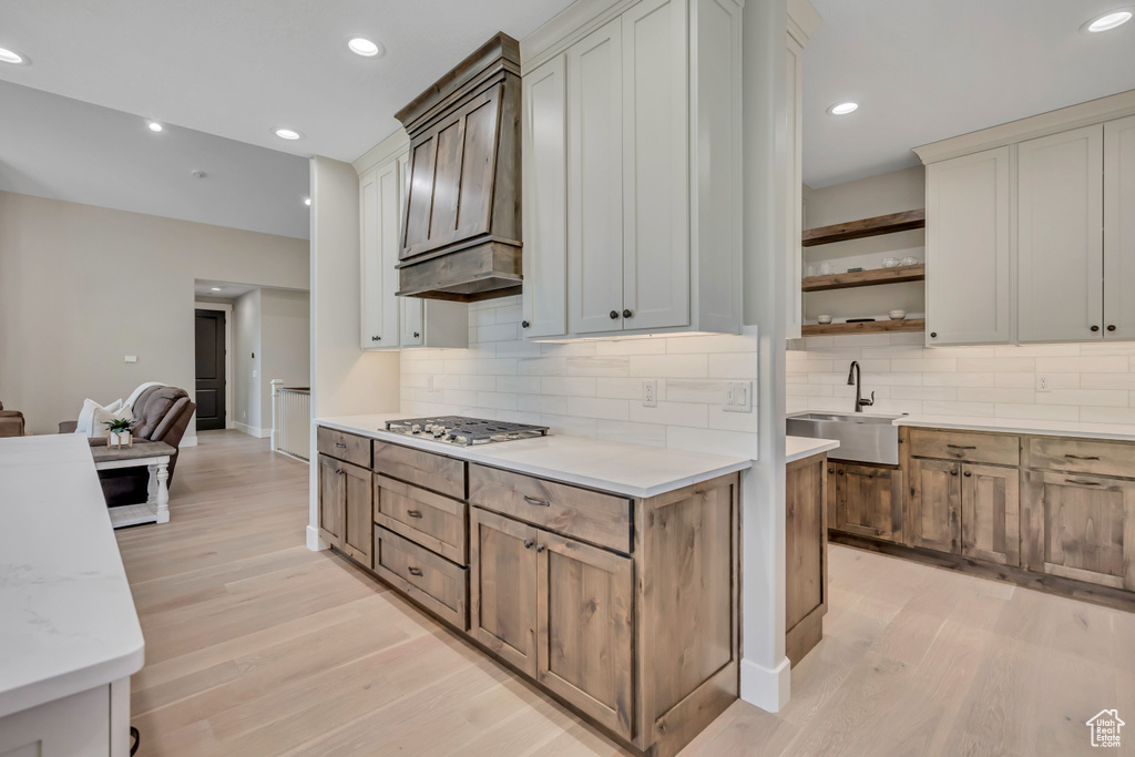 Kitchen featuring stainless steel gas stovetop, light wood-style floors, open shelves, tasteful backsplash, and recessed lighting