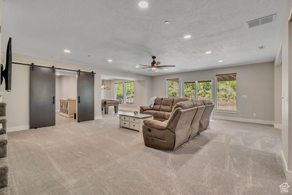 Living room with a barn door, billiards table, a ceiling fan, light colored carpet, and recessed lighting