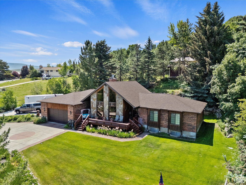 View of front of property featuring brick siding, driveway, a front lawn, and a wooden deck