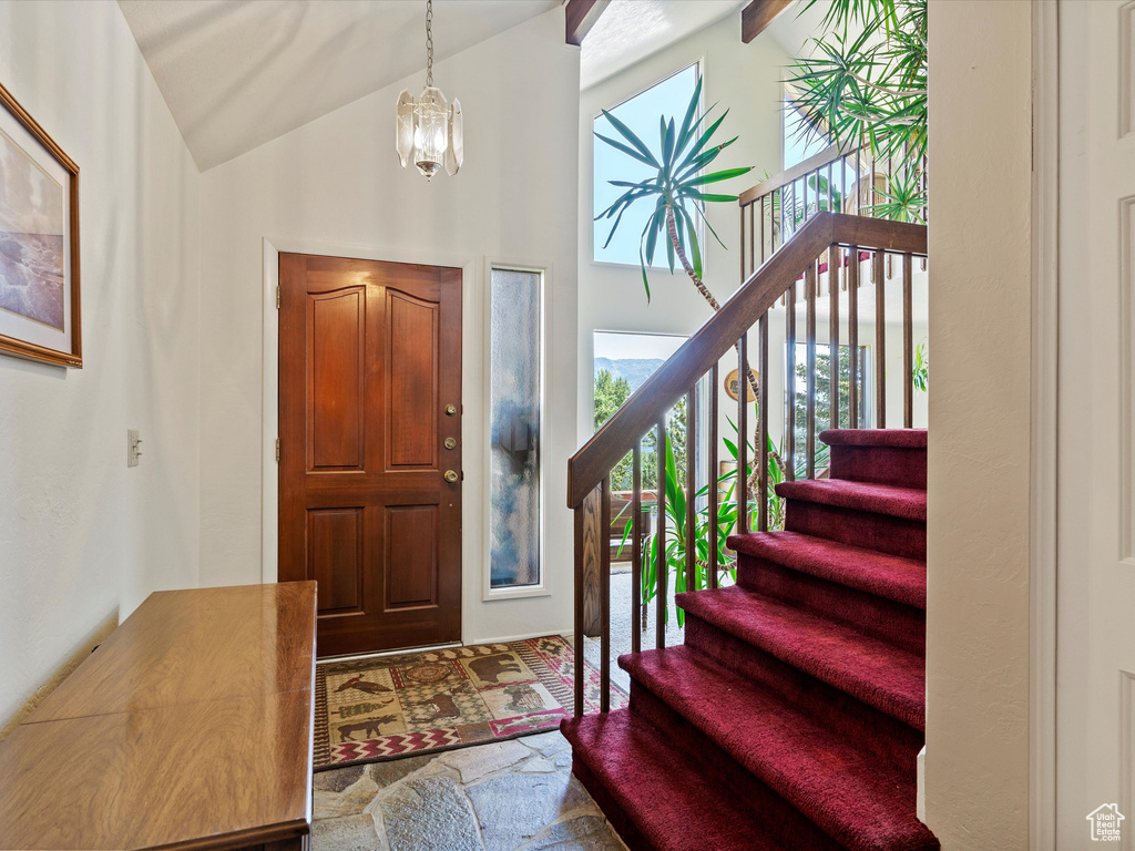 Foyer with healthy amount of natural light, stairs, a chandelier, and high vaulted ceiling