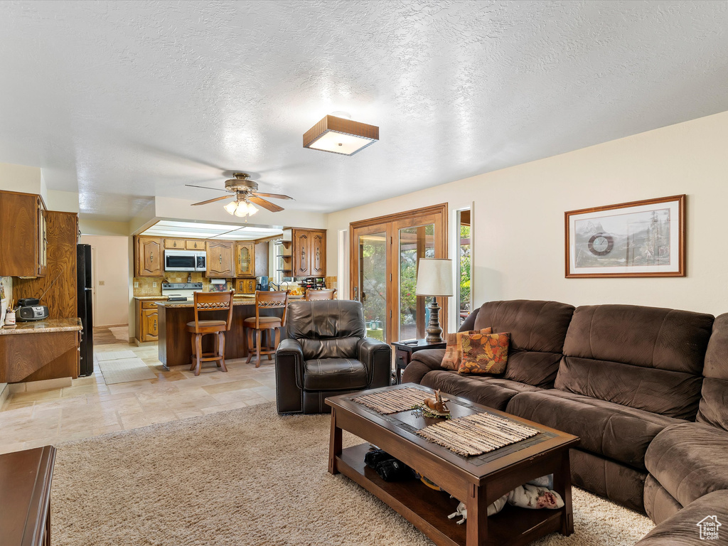 Living room with a ceiling fan and a textured ceiling