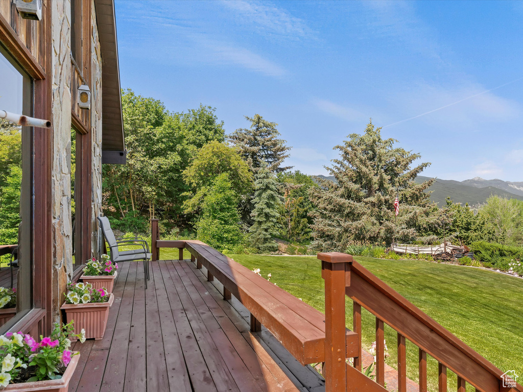 Wooden terrace featuring a lawn and a mountain view