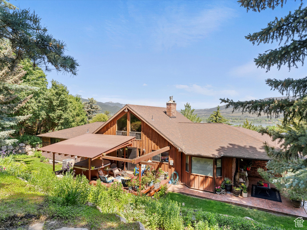 Rear view of property with a chimney, a mountain view, and roof with shingles