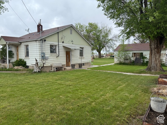 Rear view of house featuring a yard and a chimney