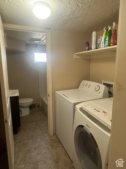 Laundry room featuring independent washer and dryer and a textured ceiling