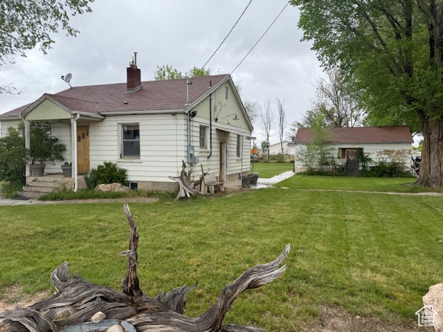 View of property exterior featuring a chimney and a yard