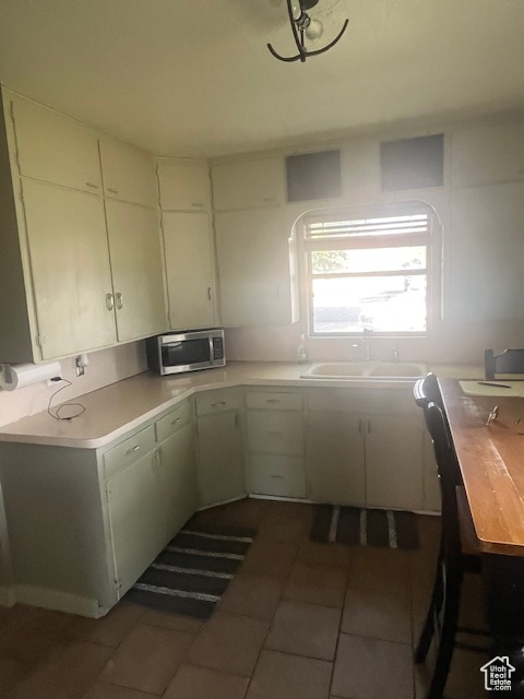 Kitchen with stainless steel microwave, light countertops, and tile patterned flooring