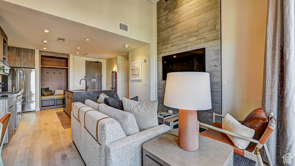 Living room featuring light wood-style flooring, a high ceiling, and recessed lighting