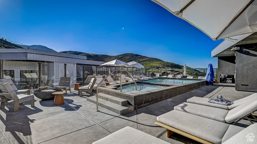 Community pool featuring a fire pit, a mountain view, a community hot tub, and a patio area