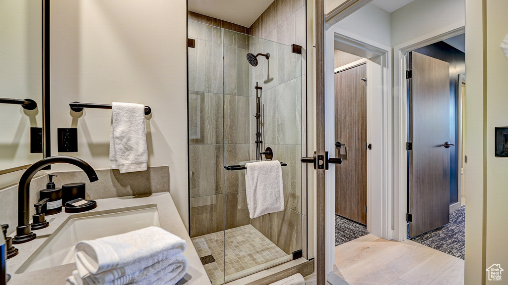 Full bath featuring a shower stall, wood finished floors, and vanity