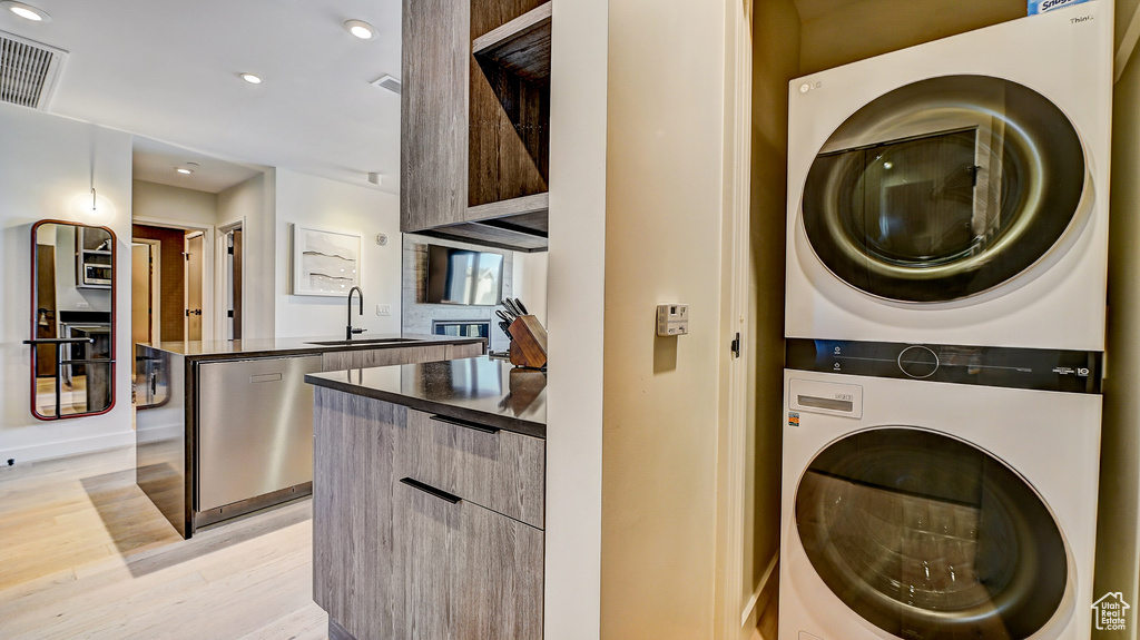 Washroom featuring estacked washer and dryer, light wood-style floors, and recessed lighting