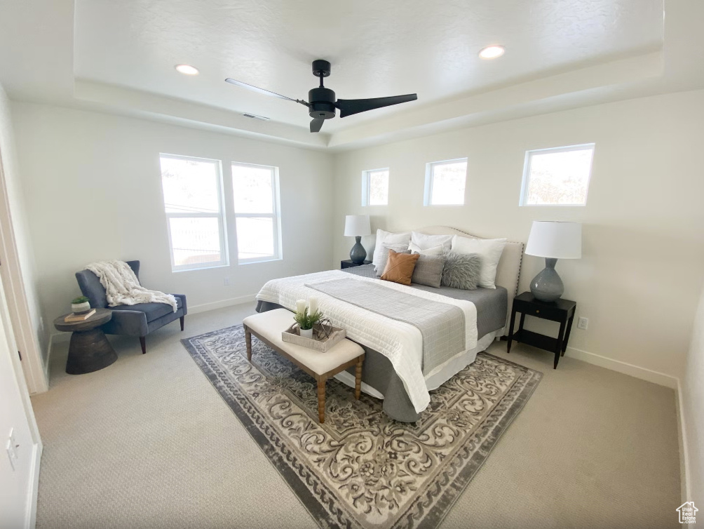 Carpeted bedroom with a tray ceiling, recessed lighting, and a ceiling fan
