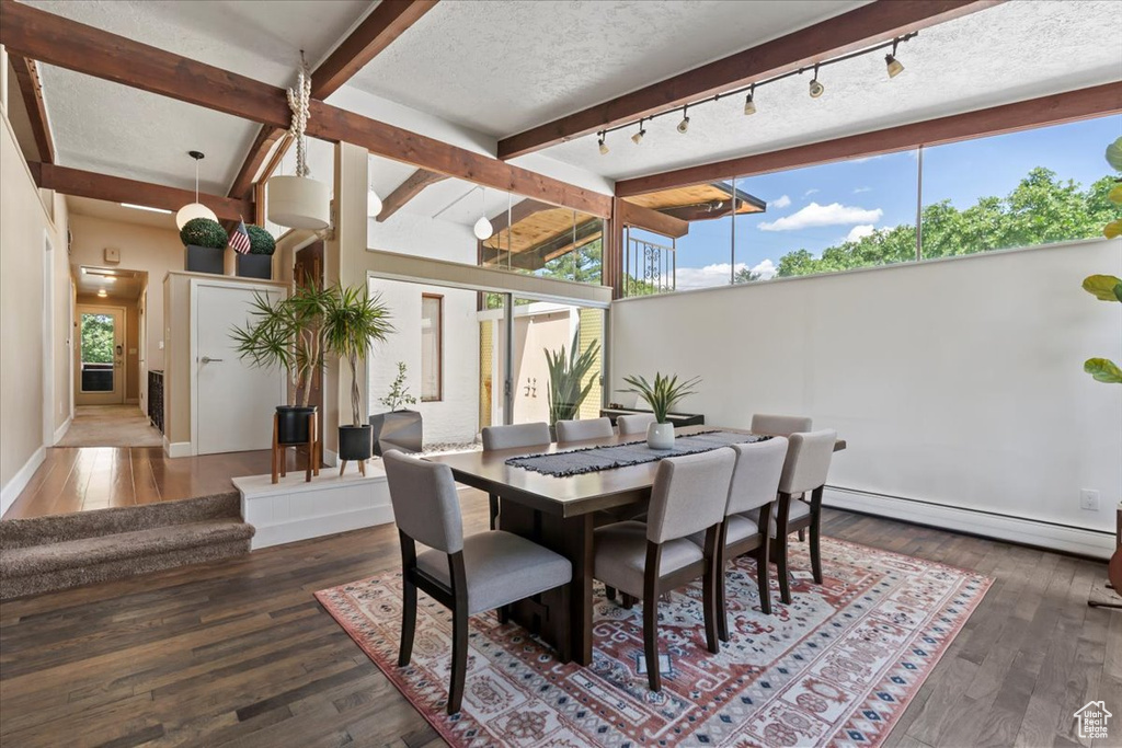 Dining space with a baseboard radiator, rail lighting, beam ceiling, and hardwood / wood-style floors