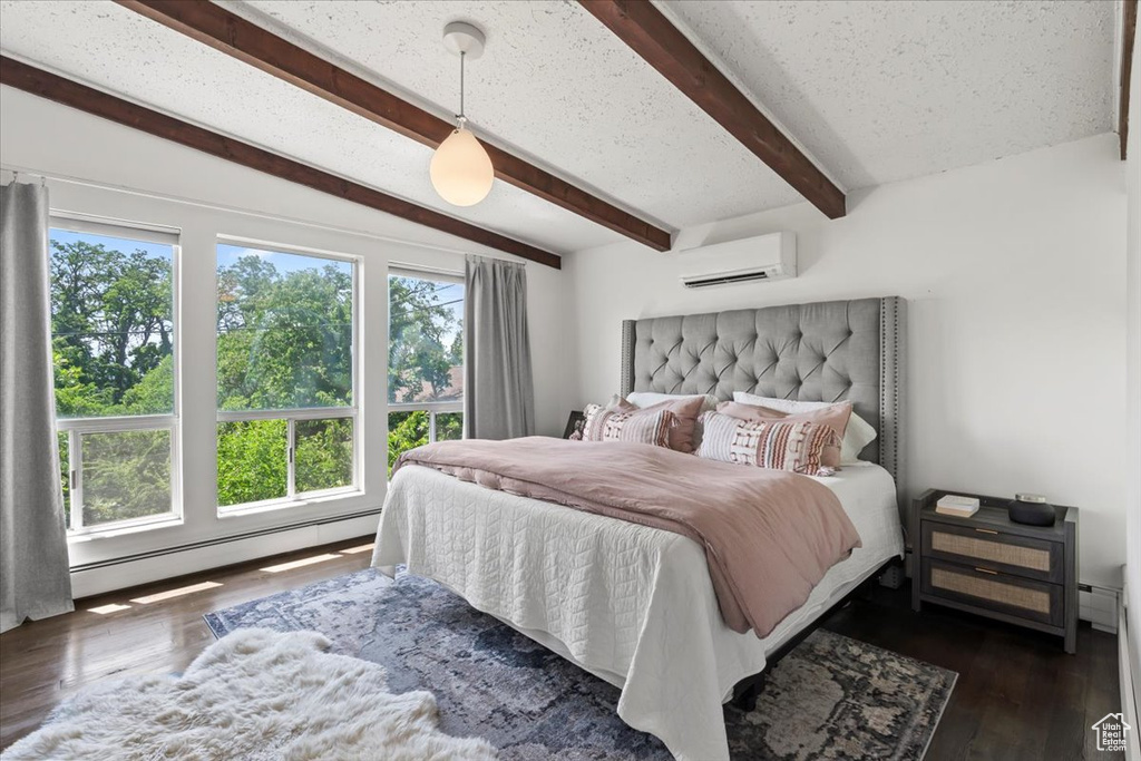 Bedroom with a wall mounted air conditioner, a baseboard radiator, beam ceiling, and dark wood finished floors