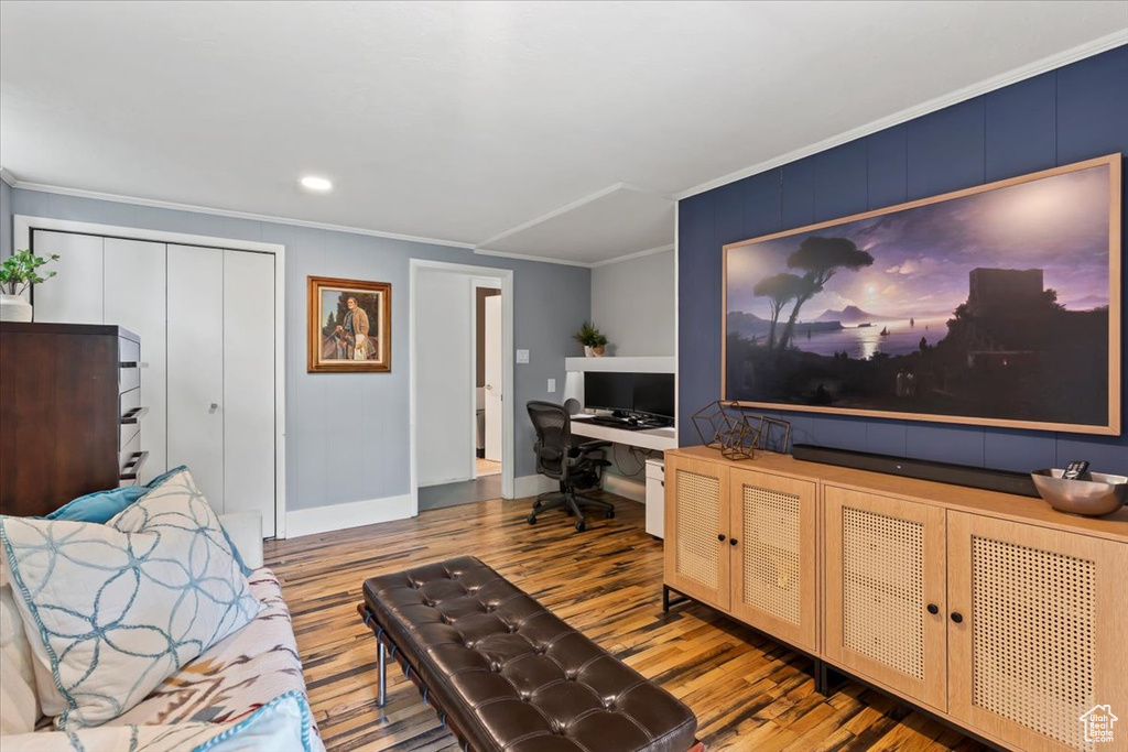 Living room featuring wood finished floors, crown molding, built in study area, and recessed lighting
